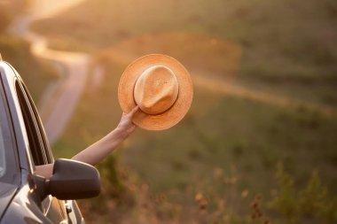 Arabasında yaz şapkası olan bir kadın yolda seyahat ediyor. Özgürlük, seyahat ve tatil yolculuğu konsept yaşam tarzı imajı