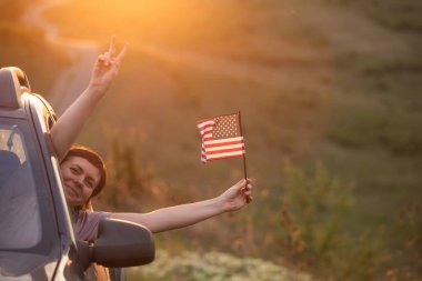 Gün batımında Amerikan bayrağı taşıyan bir kadın. Bağımsızlık Günü ya da Amerika 'da seyahat.