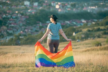 Elinde Gay Gökkuşağı Bayrağı olan bir kadın. Aynı cinsiyet çiftleri için mutluluk, özgürlük ve aşk kavramı