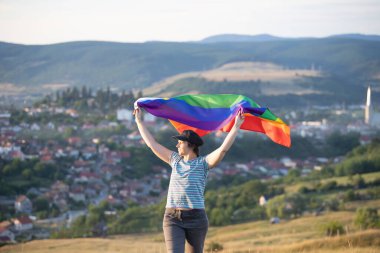 Elinde Gay Gökkuşağı Bayrağı olan bir kadın. Aynı cinsiyet çiftleri için mutluluk, özgürlük ve aşk kavramı