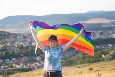Elinde Gay Gökkuşağı Bayrağı olan bir kadın. Aynı cinsiyet çiftleri için mutluluk, özgürlük ve aşk kavramı