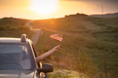 Gün batımında Amerikan bayrağı taşıyan bir kadın. Bağımsızlık Günü ya da Amerika 'da seyahat.
