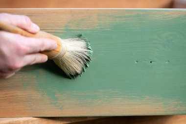 İnsan eli tebeşirle ahşap mobilya boyuyor. Yepyeni renkli tebeşir boyasıyla eski moda ahşap mobilyaları yeniliyorum. Ev dekorasyonu yeniden biçimlendiriliyor