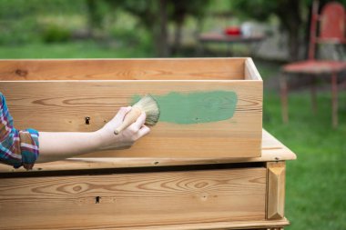 İnsan eli tebeşirle ahşap mobilya boyuyor. Yepyeni renkli tebeşir boyasıyla eski moda ahşap mobilyaları yeniliyorum. Ev dekorasyonu yeniden biçimlendiriliyor