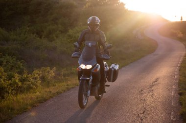 Gün batımında motosiklet süren bir adam.