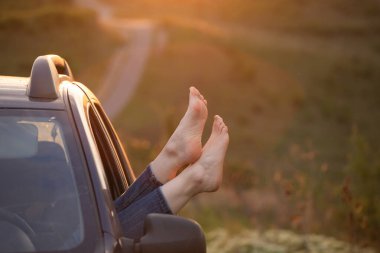 Kadının bacakları arabanın camından dışarı. Özgürlük, seyahat ve tatil gezisi konsepti yaşam tarzı imajı..
