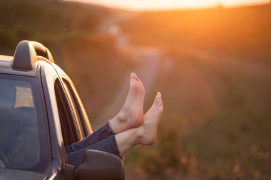 Kadının bacakları arabanın camından dışarı. Özgürlük, seyahat ve tatil gezisi konsepti yaşam tarzı imajı..