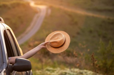 Arabasında yaz şapkası olan bir kadın yolda seyahat ediyor. Özgürlük, seyahat ve tatil yolculuğu konsept yaşam tarzı imajı