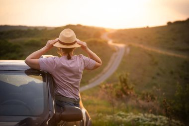 Arabasında yaz şapkası olan bir kadın yolda seyahat ediyor. Özgürlük, seyahat ve tatil yolculuğu konsept yaşam tarzı imajı