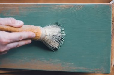 İnsan eli tebeşirle ahşap mobilya boyuyor. Yepyeni renkli tebeşir boyasıyla eski moda ahşap mobilyaları yeniliyorum. Ev dekorasyonu yeniden biçimlendiriliyor