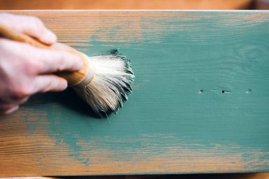 İnsan eli tebeşirle ahşap mobilya boyuyor. Yepyeni renkli tebeşir boyasıyla eski moda ahşap mobilyaları yeniliyorum. Ev dekorasyonu yeniden biçimlendiriliyor