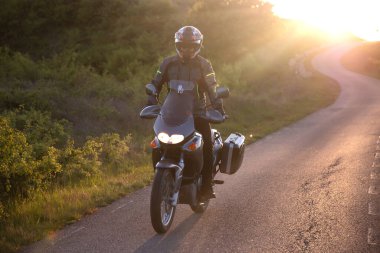 Gün batımında yolda motosiklet sürücüsü. Seyahat ve spor, hız ve özgürlük kavramı