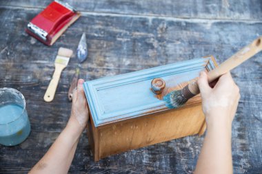 İnsan eli tebeşirle ahşap mobilya boyuyor. Yepyeni renkli tebeşir boyasıyla eski moda ahşap mobilyaları yeniliyorum..