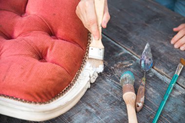 İnsan eli tebeşirle ahşap mobilya boyuyor. Yepyeni renkli tebeşir boyasıyla eski moda ahşap mobilyaları yeniliyorum. Ev dekorasyonu yeniden biçimlendiriliyor