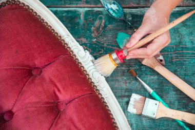 İnsan eli tebeşirle ahşap mobilya boyuyor. Yepyeni renkli tebeşir boyasıyla eski moda ahşap mobilyaları yeniliyorum. Ev dekorasyonu yeniden biçimlendiriliyor