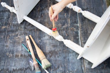 İnsan eli tebeşirle ahşap mobilya boyuyor. Yepyeni renkli tebeşir boyasıyla eski moda ahşap mobilyaları yeniliyorum. Ev dekorasyonu yeniden biçimlendiriliyor