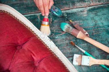 İnsan eli tebeşirle ahşap mobilya boyuyor. Yepyeni renkli tebeşir boyasıyla eski moda ahşap mobilyaları yeniliyorum. Ev dekorasyonu yeniden biçimlendiriliyor