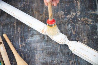 İnsan eli tebeşirle ahşap mobilya boyuyor. Yepyeni renkli tebeşir boyasıyla eski moda ahşap mobilyaları yeniliyorum. Ev dekorasyonu yeniden biçimlendiriliyor