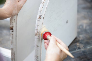 İnsan eli tebeşirle ahşap mobilya boyuyor. Yepyeni renkli tebeşir boyasıyla eski moda ahşap mobilyaları yeniliyorum. Ev dekorasyonu yeniden biçimlendiriliyor