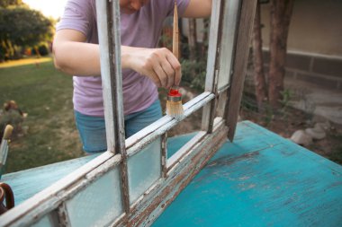 Evdeki klasik bir pencereyi boyayan orta yaşlı kadın, taşınma ve diy konsepti..