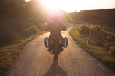 Gün batımında yolda motosiklet sürücüsü. Seyahat ve spor, hız ve özgürlük kavramı