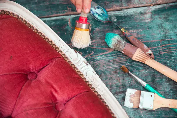 İnsan eli tebeşirle ahşap mobilya boyuyor. Yepyeni renkli tebeşir boyasıyla eski moda ahşap mobilyaları yeniliyorum. Ev dekorasyonu yeniden biçimlendiriliyor
