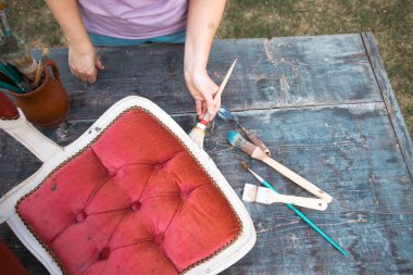 İnsan eli tebeşirle ahşap mobilya boyuyor. Yepyeni renkli tebeşir boyasıyla eski moda ahşap mobilyaları yeniliyorum. Ev dekorasyonu yeniden biçimlendiriliyor