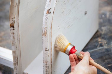 İnsan eli tebeşirle ahşap mobilya boyuyor. Yepyeni renkli tebeşir boyasıyla eski moda ahşap mobilyaları yeniliyorum. Ev dekorasyonu yeniden biçimlendiriliyor