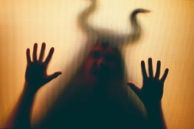 Karanlıkta, pencerenin arkasında boynuzları olan ürkütücü bir figür. Cadılar Bayramı geçmişi 