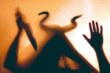 Karanlıkta, pencerenin arkasında elinde bıçak olan ürkütücü bir figür. Cadılar Bayramı geçmişi