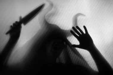 Karanlıkta, pencerenin arkasında elinde bıçak olan ürkütücü bir figür. Cadılar Bayramı geçmişi