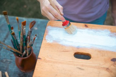 İnsan eli tebeşirle ahşap mobilya boyuyor. Yepyeni renkli tebeşir boyasıyla eski moda ahşap mobilyaları yeniliyorum. Ev dekorasyonu yeniden biçimlendiriliyor