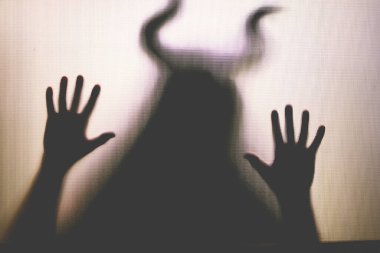 Karanlıkta, pencerenin arkasında boynuzları olan ürkütücü bir figür. Cadılar Bayramı geçmişi 