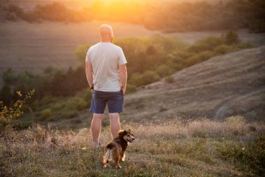 Doğada bir adam ve köpeği güzel bir gün batımında.