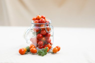 Cam kavanozda fesleğen yapraklı kiraz domatesleri. Sonbahar ya da kış için yiyecek. Ev yapımı hazırlıklar.