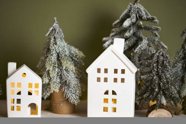 Mutlu Noeller ve mutlu yıllar! Şenlikli Noel sahnesi, minyatür tatil köyü. Şık Noel ağaçları ve yeşil arka planda küçük evler.