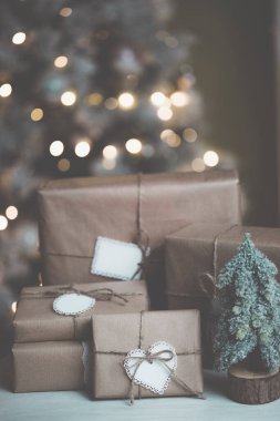 Noel arkaplanı çevre dostu paketleme hediyeleriyle Kraft kağıdında beyaz ahşap bir masa üzerinde Noel süslemeli odada.