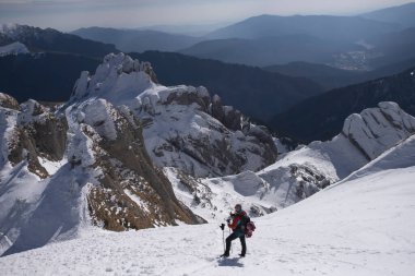 Yürüyüşçü karlı dağa tırmanıyor.