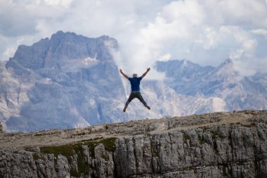 Dolomitlerle dağın tepesine atlayan mutlu bir adam. Spor ve seyahat yaşam tarzı konsepti