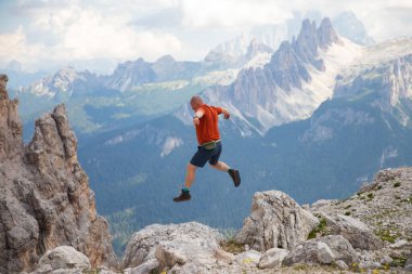 Gezgin ya da gezgin Dolomite dağlarında büyük kayalara atlıyor. Meydan okuma, risk ve özgürlük kavramı.