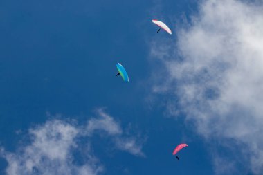 Mavi gökyüzünde bulutlarla uçan paragliderler. Macera konsepti..