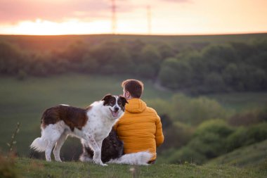 İnsan doğada köpekleriyle gün batımında.