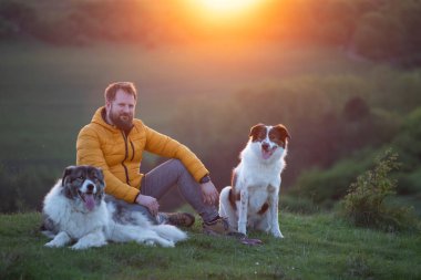 İnsan doğada köpekleriyle gün batımında.