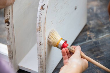 İnsan eli tebeşirle ahşap mobilya boyuyor. Yepyeni renkli tebeşir boyasıyla eski moda ahşap mobilyaları yeniliyorum. Ev dekorasyonu yeniden biçimlendiriliyor