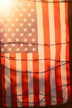 Amerikan Bayrağı, ABD sınırındaki dikenli tellere bağlı. Amerikan göçmenlik ve ABD mülteci krizi kavramı