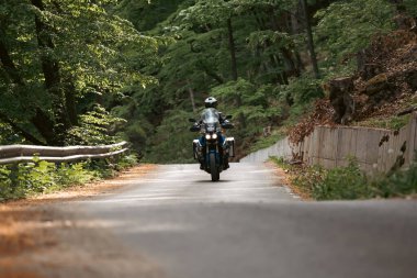 Ormanda motorsikletli bir adam. Seyahat ve spor, hız ve özgürlük kavramı.