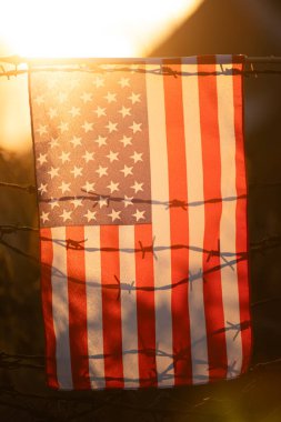 Amerikan Bayrağı, ABD sınırındaki dikenli tellere bağlı. Amerikan göçmenlik ve ABD mülteci krizi kavramı