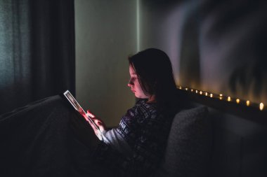 Akıllı telefon kullanan genç kız, gece geç saatte yatakta yatan tablet. Çocukların ekran bağımlılığı konsepti..