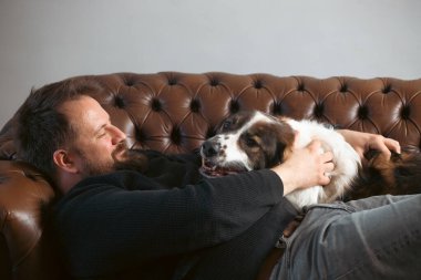 Evinde sevimli, mutlu köpeğiyle beyaz yakışıklı bir adam..