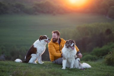 İnsan doğada köpekleriyle gün batımında.